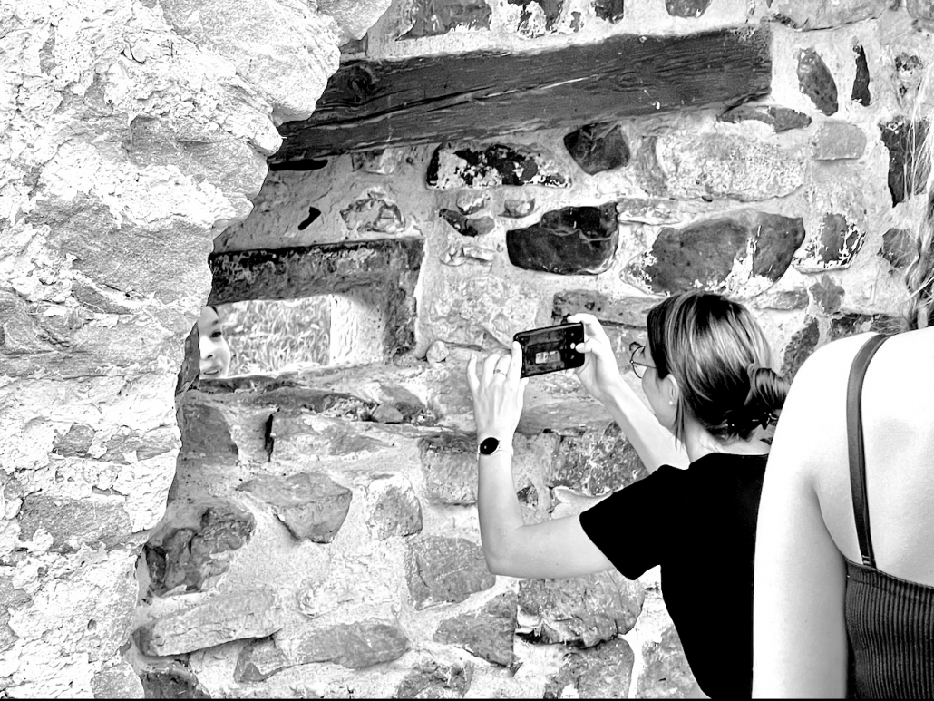 Eine Betreuerin fotografiert durch ein Loch in einer alten Steinwand - Version 3