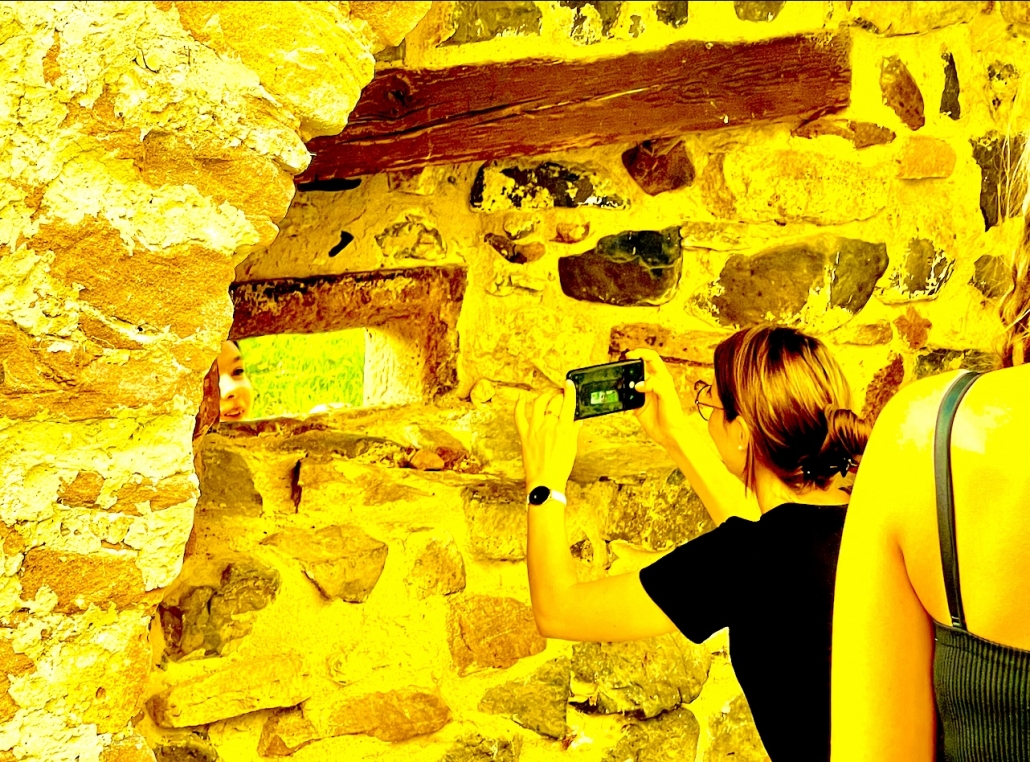 Eine Betreuerin fotografiert durch ein Loch in einer alten Steinwand - Version 1