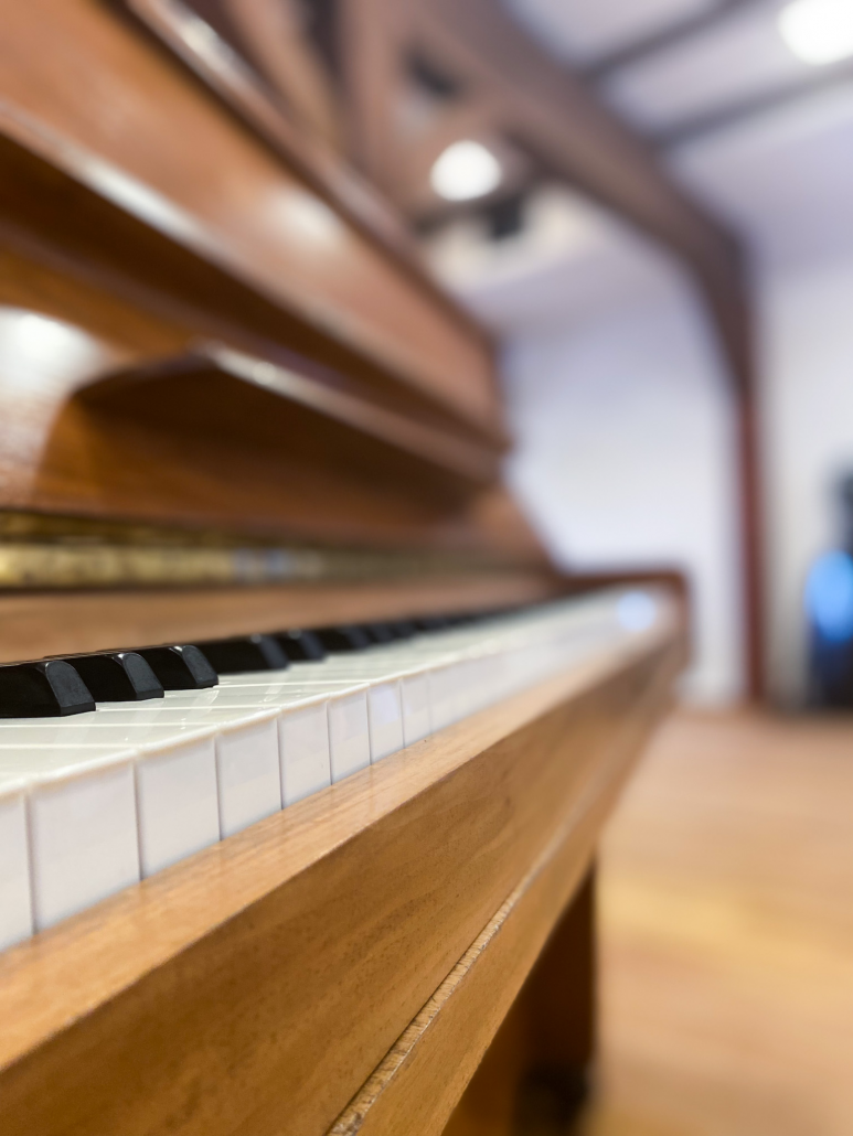 Eine Klaviertastatur-Nahaufnahme mit Holzbalken im Raum dahinter