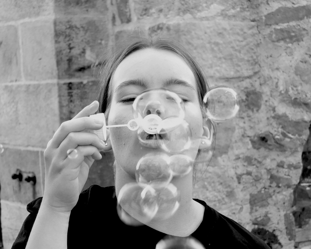 Nahaufnahme einer Schülerin beim Seifenblasen machen (schwarz-weiß)