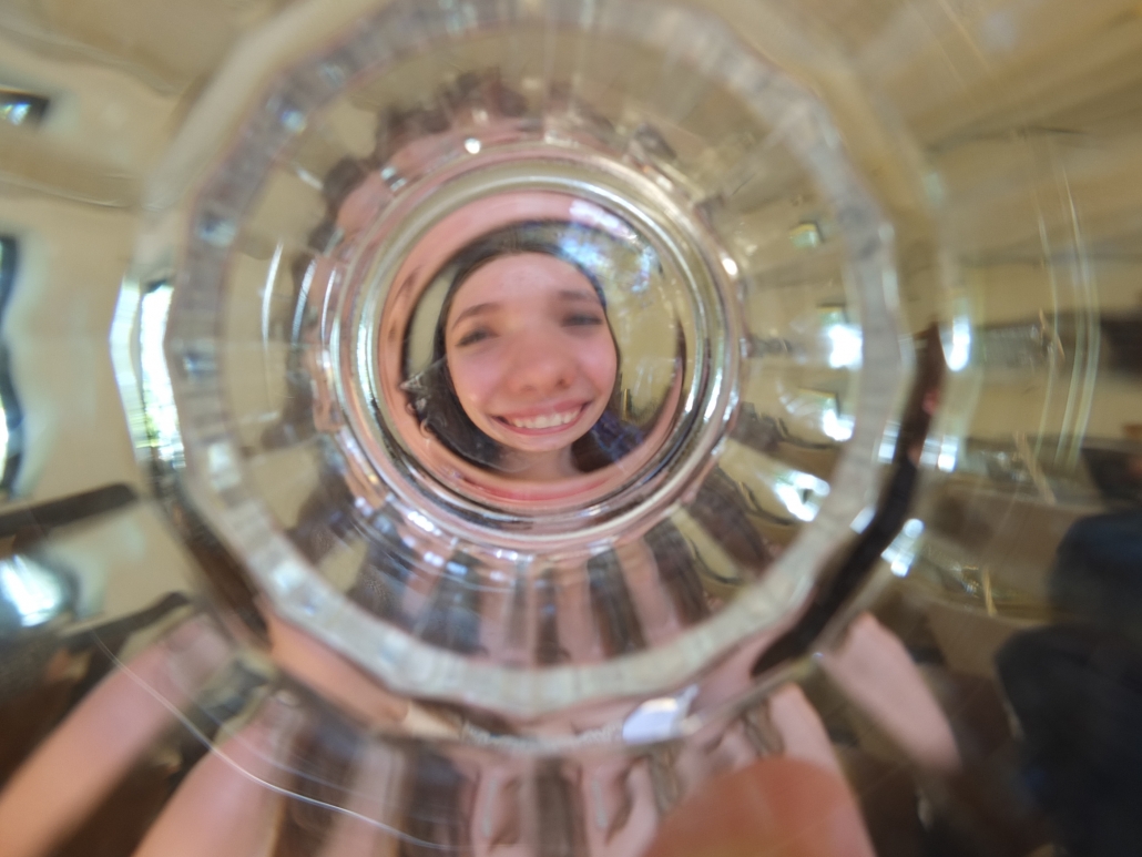 Schülerin fotografiert durch ein Glas